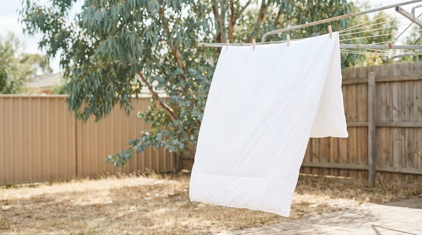 A white doona pegged over an outdoor clothesline in a sunny Australian backyard